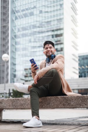 Foto de Joven americano hombre usando smartphone sentado al aire libre - Imagen libre de derechos