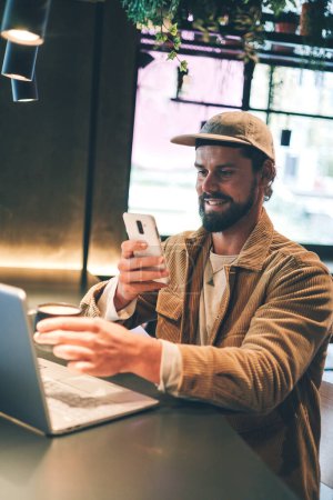 Foto de Hombre caucásico en un café posteando una foto de su café y portátil. Foto de alta calidad. - Imagen libre de derechos