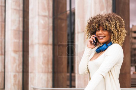Foto de Mujer afro dominicana usando smartphone y sonriendo a la cámara. Foto de alta calidad - Imagen libre de derechos