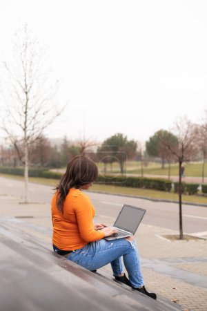 Photo for Rear view of trans woman using laptop in campus stairs. General view of campus. High quality photo - Royalty Free Image