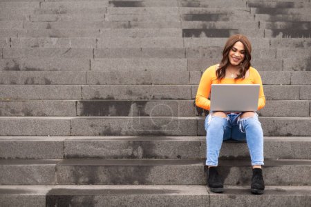 Photo for Trans woman student using laptop in university stairs. Copy space in stairs. High quality photo - Royalty Free Image