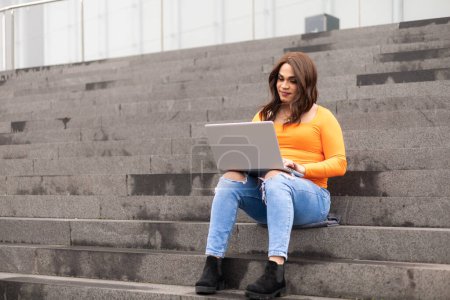 Photo for Trans woman student using laptop in university stairs. High quality photo - Royalty Free Image