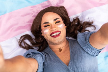 Foto de Mujer transgénero feliz acostada en una bandera trans. Vista desde arriba. Abran los brazos. Concepto LGTB. Foto de alta calidad - Imagen libre de derechos