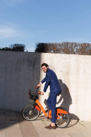 Attraktiver Geschäftsmann, der Fahrrad fährt und in die Kamera lächelt. Hochwertiges Foto