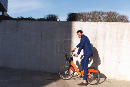 Attractive businessman riding a bike and smiling to the camera. High quality photo