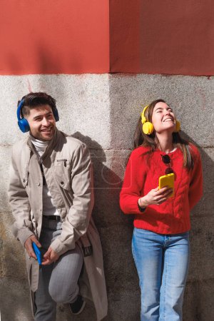 Téléchargez les photos : Jeune homme et jeune femme écoutant de la musique et appréciant leur compagnie. Espace de copie vertical. Photo de haute qualité - en image libre de droit