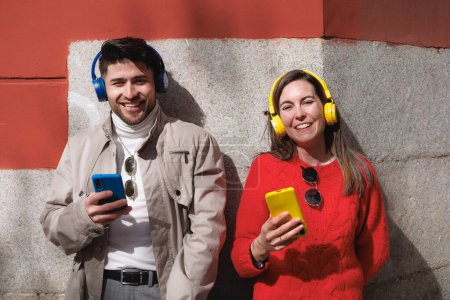 Téléchargez les photos : Portrait d'un couple d'amis latins utilisant un téléphone portable et écoutant de la musique. Génération Z. Photo de haute qualité - en image libre de droit