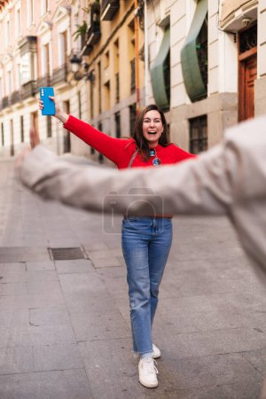 Z generation woman opening arms and meeting her best friend in the street. High quality photo