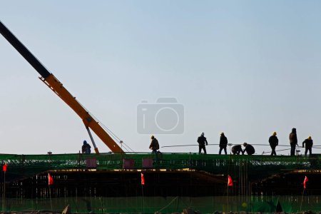 Foto de Estructura de hormigón armado, los trabajadores en el sitio de construcción en silueta - Imagen libre de derechos