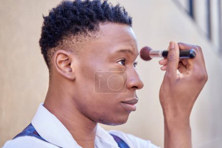 young african-american man putting make-up on his face