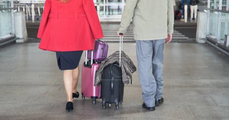 Together on the go: Unrecognizable couple with travel bags walking in sync