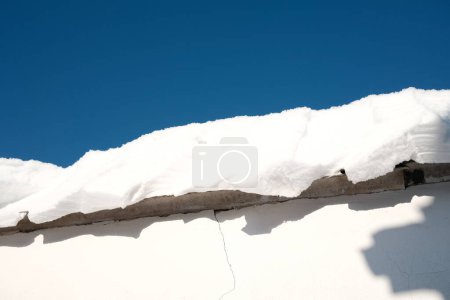 Téléchargez les photos : Neige sur le toit d'une maison par temps ensoleillé - en image libre de droit