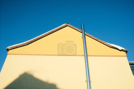 Téléchargez les photos : Maison jaune avec une pipe et un ciel bleu - en image libre de droit