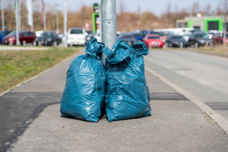 Téléchargez les photos : Sacs poubelle dans la rue près du poteau métallique - en image libre de droit