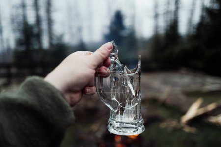 Téléchargez les photos : Homme tenant tasse en verre cassé dans la forêt - en image libre de droit