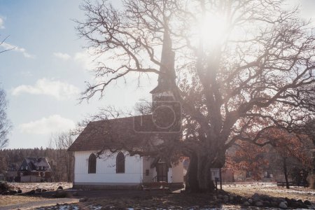 Téléchargez les photos : Vieille église en bois en hiver avec grand arbre - en image libre de droit