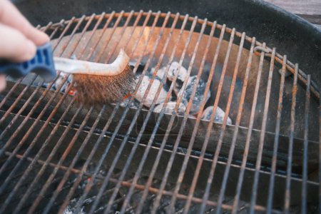 Photo for Cleaning of barbecue grill with iron brush - Royalty Free Image