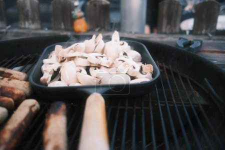 Photo for Cooking sausages and mushrooms on a grill. - Royalty Free Image