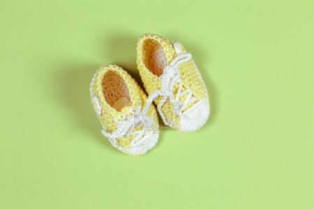 Photo for Yellow knitted baby shoes on green  background - Royalty Free Image