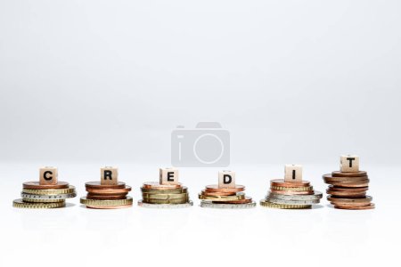 Photo for Piles of coins with word credit on white background - Royalty Free Image