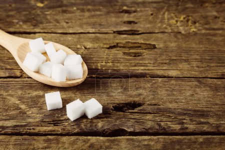 Photo for Sugar cubes in spoon on a rustic wooden table - Royalty Free Image