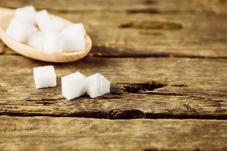 Téléchargez les photos : Cuillère de cubes blancs de sucre sur une table en bois - en image libre de droit