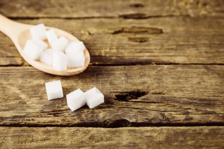 Foto de Cuchara de cubos blancos de azúcar en una mesa de madera - Imagen libre de derechos