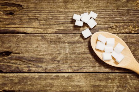 Photo for Sugar cubes in spoon on a rustic wooden table - Royalty Free Image