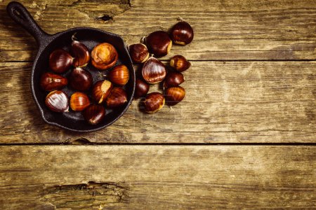 Photo for Chestnuts in pan on the old wooden table - Royalty Free Image