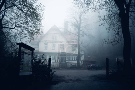 casa en la niebla con un coche estacionado en frente
