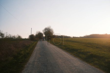 Téléchargez les photos : Randonneurs avec sacs à dos debout sur la route rurale pendant le coucher du soleil - en image libre de droit