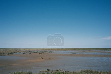 picturesque view of outdoor scene with water, grass and blue sky