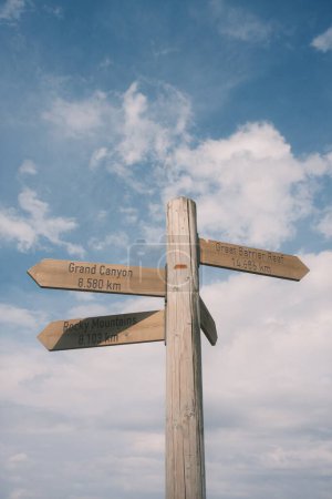 closeup shot of wooden signpost with arrows signs on sky background