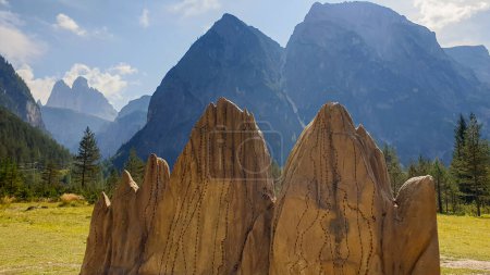 Photo for A miniature of Drei Zinnen with the view on the real mountains in the back in Italian Dolomites. Many high mountains around. A lush green meadow in front with a few pine trees in between. Sunny day. - Royalty Free Image