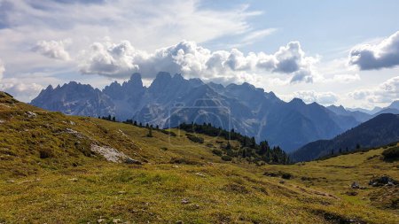 Photo for A panoramic view on the high Italian Dolomites from the top of Strudelkopf. There is a wide gravelled path leading to the top. Sunny day. A few clouds above the high peaks. Lush green plateau around - Royalty Free Image