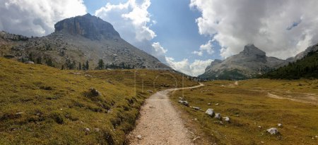 Téléchargez les photos : Une route gravelée qui traverse les Dolomites italiennes. Des montagnes hautes et pointues. Les pentes et les prairies sont dorées, les parties supérieures sont stériles et pierreuses. Couvert. Endroit isolé et désolé. Liberté - en image libre de droit