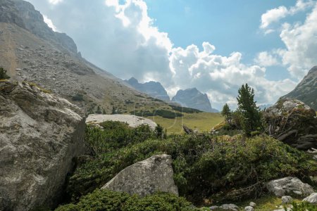 Téléchargez les photos : Vue rapprochée sur un massif rocheux recouvert de buissons dans les Dolomites italiennes. Il y a des montagnes hautes et pointues à l'arrière. Paysage isolé et désolé. Un peu de ciel couvert - en image libre de droit