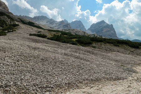Téléchargez les photos : Un énorme glissement de terrain dans les Dolomites italiennes. Toute la zone est pleine de petites pierres et de cailloux. À l'arrière, il y a des chaînes de haute montagne. Zone crue et désolée. Paysage dangereux. Un peu de ciel couvert - en image libre de droit