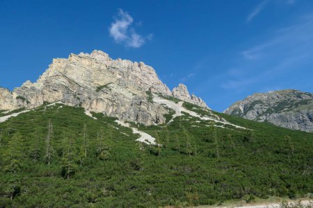 Téléchargez les photos : Vue lointaine sur une haute montagne dans les Dolomites italiennes. Il a des pentes très raides, plein de glissements de terrain et de perdre des pierres. Forêt épaisse au pied de la montagne. Haute alpinisme. Expérience - en image libre de droit