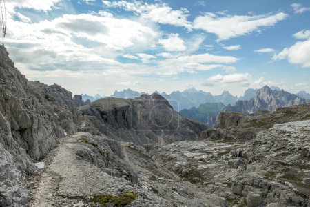 Foto de Una vista sin fin sobre una montaña alta y desolada picos en Dolomitas italianas. Las partes más bajas de las montañas están cubiertas de musgo y hierba. Paisaje crudo y virgen. Pocas nubes sobre los picos - Imagen libre de derechos