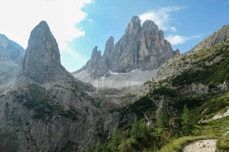 Foto de Una vista panorámica de los Dolomitas italianos. Hay muchos picos altos y agudos en frente, con muchos deslizamientos de tierra. Escalada peligrosa. Hay pocos árboles y arbustos en el lado. Paisaje crudo y virgen - Imagen libre de derechos