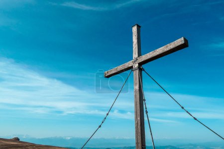 Foto de A wooden cross on top of Sauofen in Austrian Alps. Fall vibes. Mountain chains in the back. Panoramic view. There are a few white clouds on the sky. Achievement and spirituality - Imagen libre de derechos