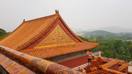 Photo for A close up on the rooftop of a pavilion in Summer Palace in Beijing, China. The roof has orange tiles and decorative small figures of guardians at the edges. Overcast. A few tree branches on the side - Royalty Free Image