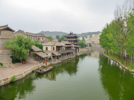 Photo for A view on the river in a small village in northern China. The river is overgrown with green plankton. Houses on both sides of the river. Serenity and calmness. Overcast due to the air pollution - Royalty Free Image