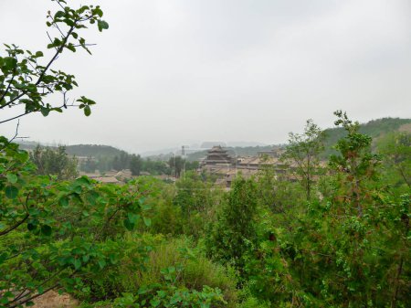 Photo for A panoramic view on a small village in northern China. There is a dense forest around the village. Rural areas. Tradition meets modernisation. Overcast due to the air pollution - Royalty Free Image