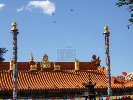 Photo for A close up on red rooftop of a Buddhist temple with golden decorations on it in Hohhot, Inner Mongolia. The gold decorations depict two deer and a golden eye in the middle. Spirituality - Royalty Free Image