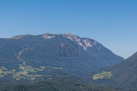 Photo for A close up view on Dobratsch, a mountain in Austrian Alps. The mountain's sides are overgrown with lush forest, Peak is baren and sharp. High mountaineering. Clear and blue sky. Calmness. - Royalty Free Image