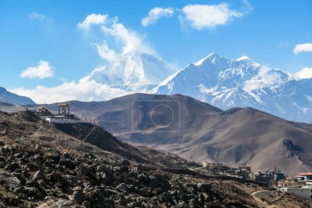 Photo for A Buddhist temple located on a steep slope in Muktinath, along Annapurna Circuit Trek in Nepal. The temple is richly ornated. In the back there is a high, snow capped Himalayan chain. Spirituality - Royalty Free Image
