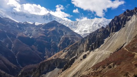 Téléchargez les photos : Pentes dures et dorées sur le chemin du camp de base de Tilicho, Annapurna Circus Trek, Himalaya, Népal, avec vue sur les hauts sommets enneigés. Paysage sec et désolé. Liberté - en image libre de droit