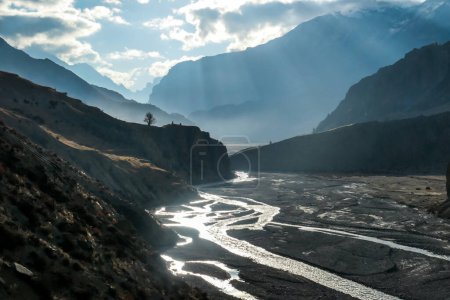 Téléchargez les photos : Une rivière brillante dans la vallée de Manang, capturée au lever du soleil, Circuit Annapurna, Népal. Le soleil se lève au-dessus des sommets de l'Himalaya. Il y a un petit village. Sérénité et calme. Nouveau départ - en image libre de droit